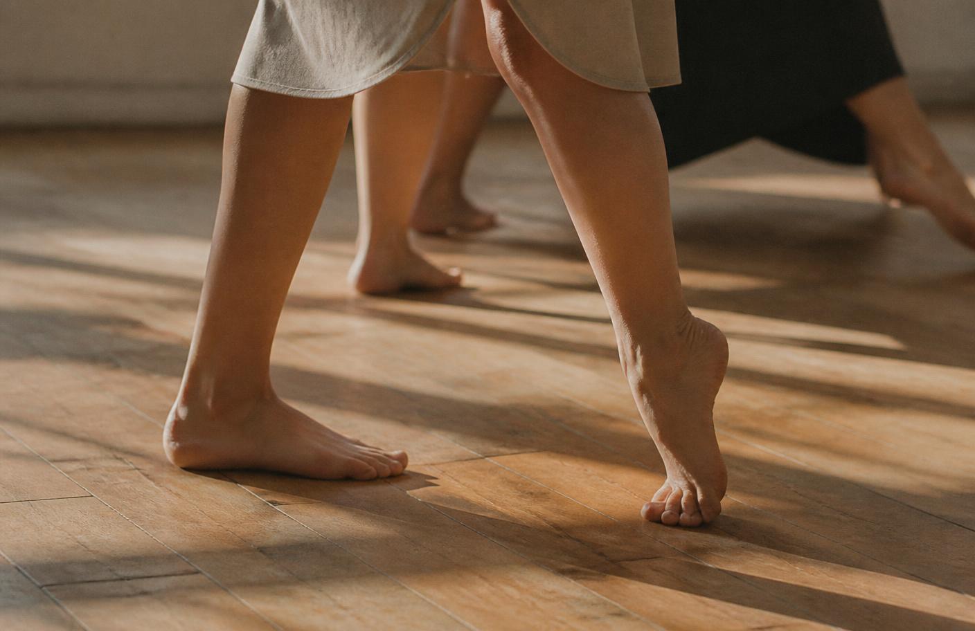 Dancers' bare feet on a warm wooden studio floor